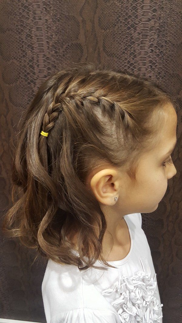 Una niña con una trenza en el pelo lleva una camisa blanca.
