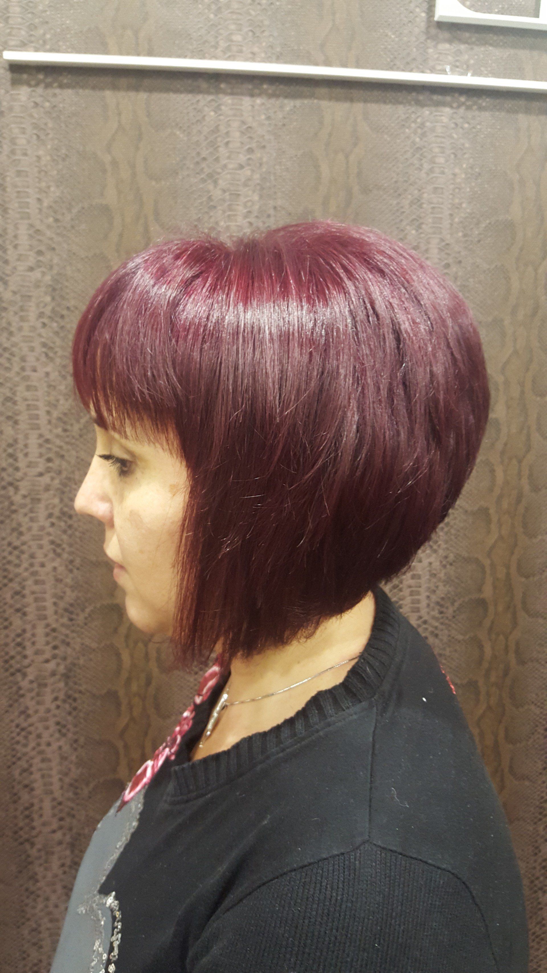 Una mujer con cabello rojo lleva un suéter negro y un collar.