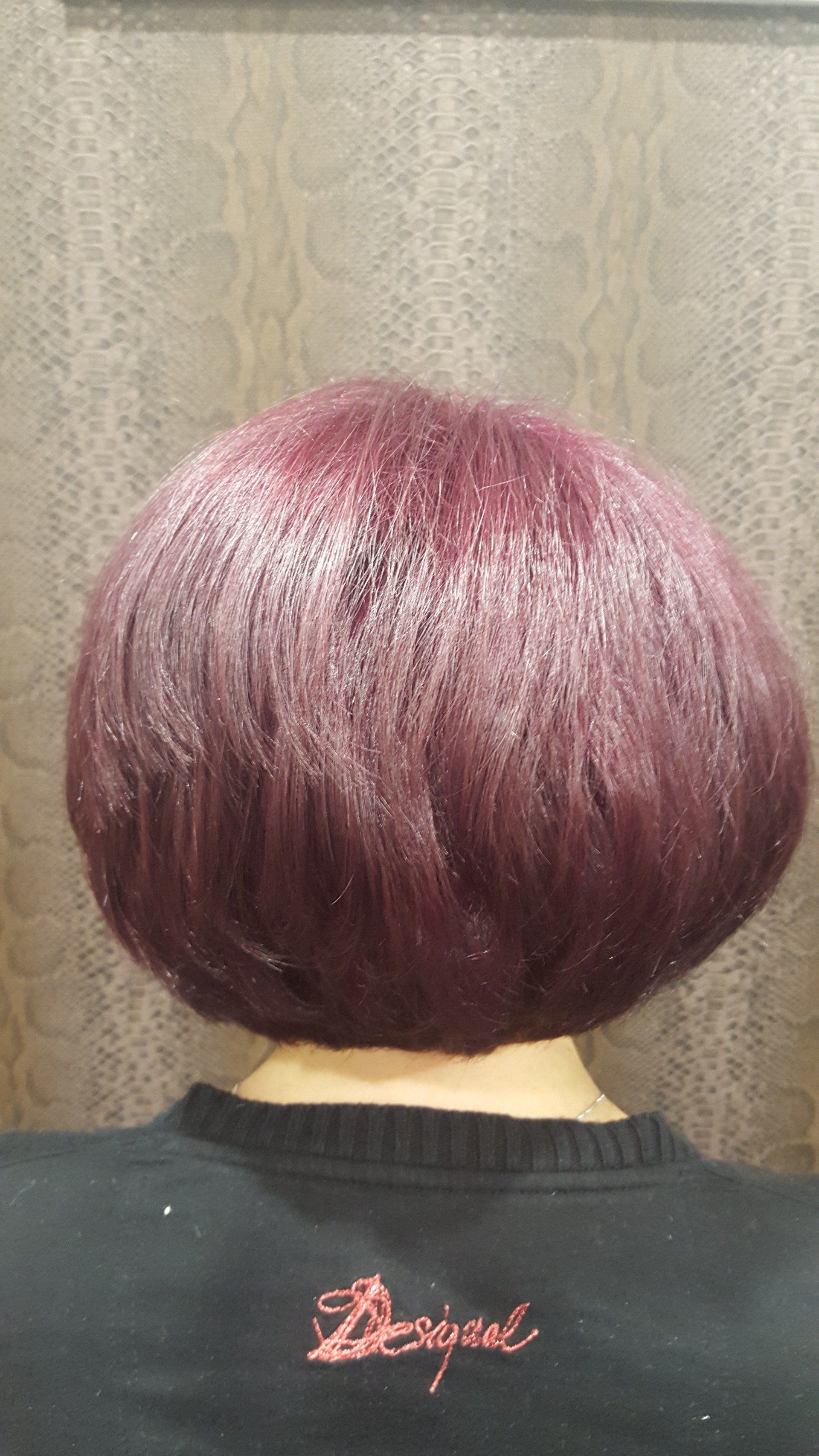 Una mujer con cabello morado lleva un suéter negro.
