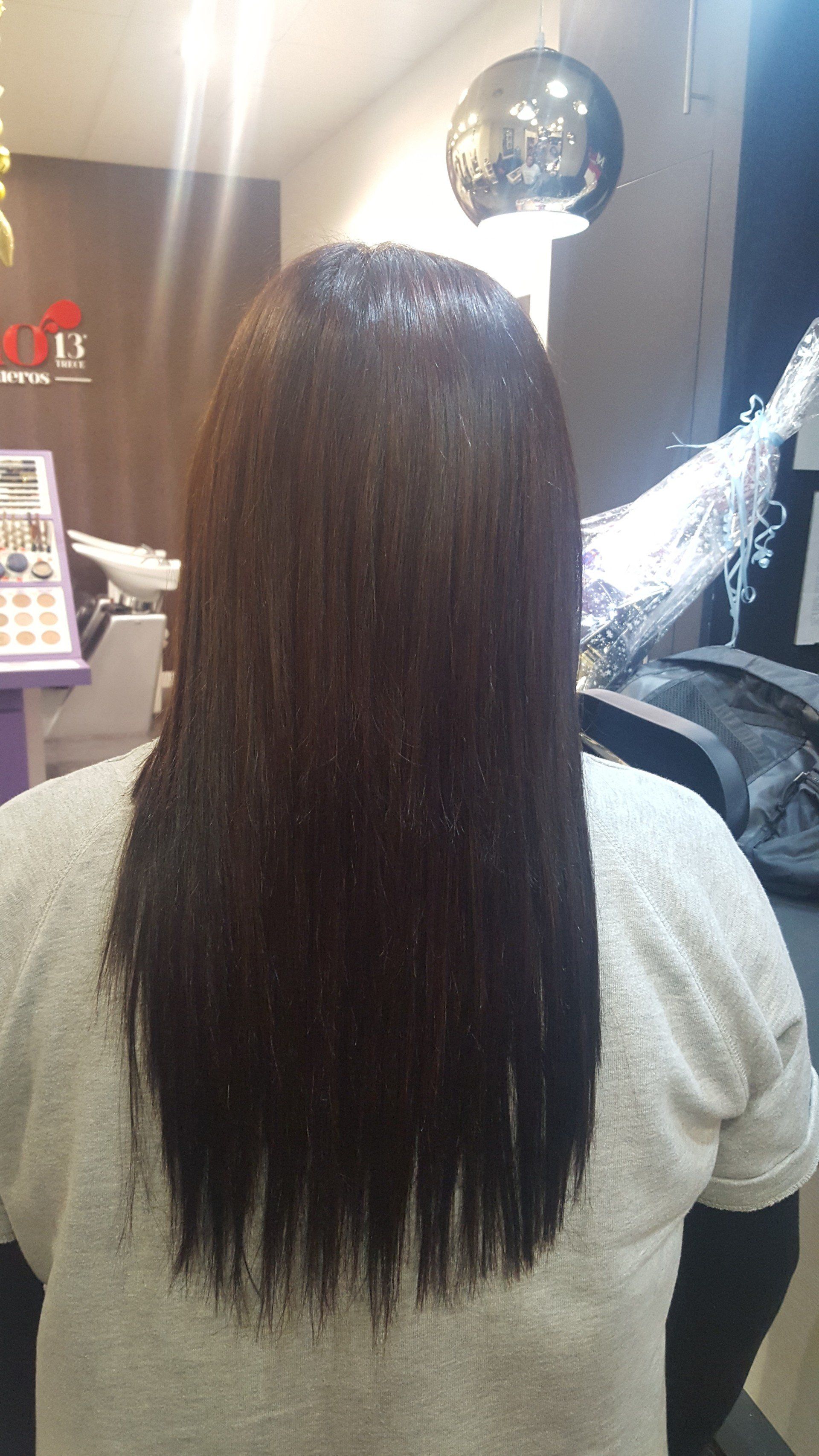 Una mujer con cabello largo está sentada en una silla en un salón.