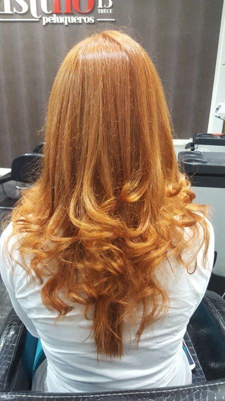 Una mujer con cabello largo y rojo está sentada en una silla en un salón.