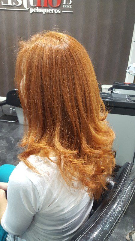 Una mujer con cabello largo y rojo está sentada en una silla en un salón.