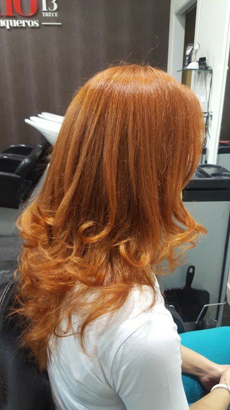 Una mujer con cabello largo y rojo está sentada en una silla en un salón.