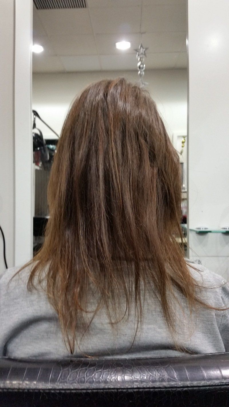 Una mujer está sentada en una silla con el cabello teñido en un salón.