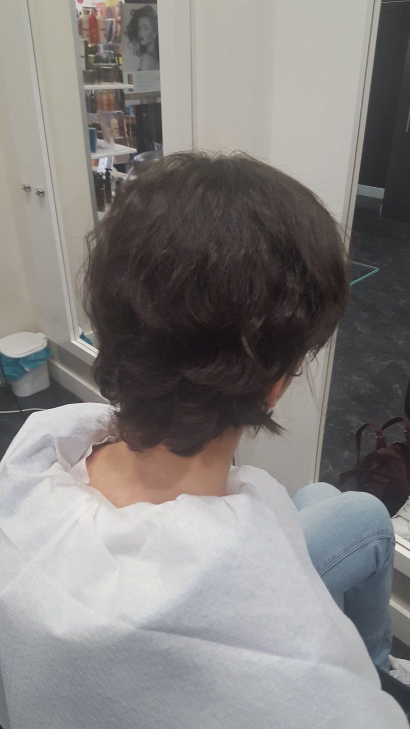 Una mujer está sentada en una silla con el cabello recogido en una trenza.