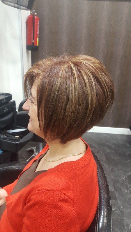 Una mujer está sentada en una silla con el pelo cortado en un salón.