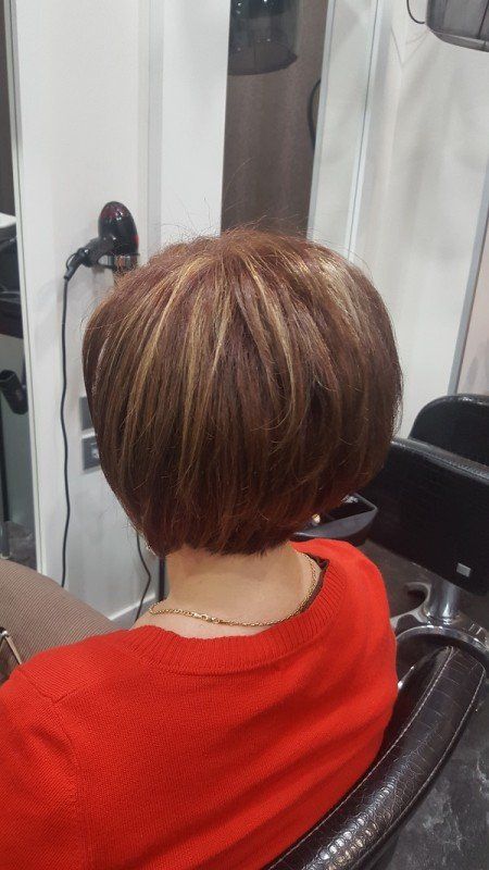 Una mujer con una camisa roja se está cortando el pelo en una peluquería.