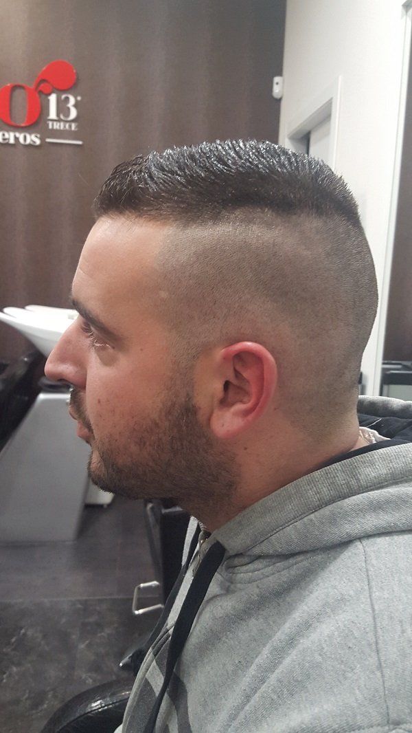 Un hombre con un peinado mohawk está sentado en una silla en un salón.