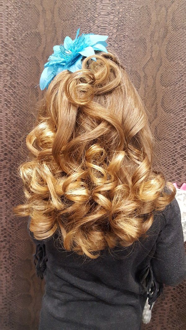 Una niña con cabello rizado y una flor azul en el pelo.