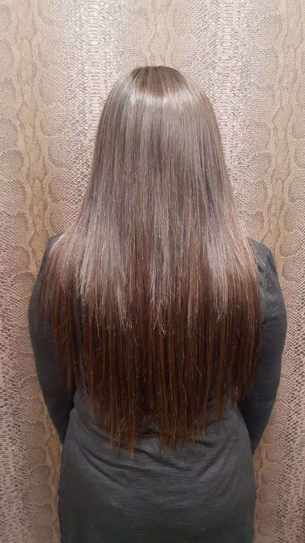 Una mujer con cabello largo y castaño está parada frente a una pared.