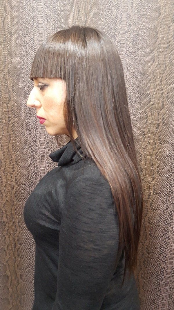 Una mujer con cabello largo y castaño y flequillo lleva un suéter de cuello alto negro.