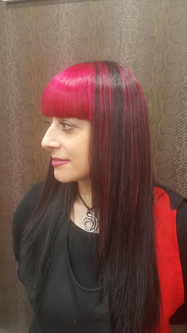 Una mujer con cabello rojo y negro lleva una camisa negra y una bufanda roja.