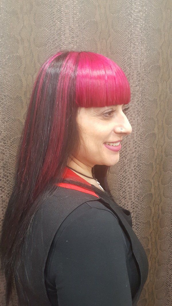 Una mujer con cabello rojo y negro y una camisa negra está sonriendo.