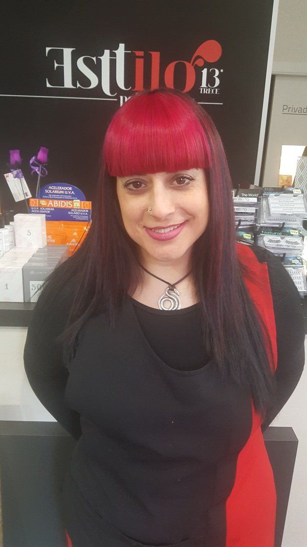 Una mujer con cabello rojo está parada frente a un cartel que dice estilo.