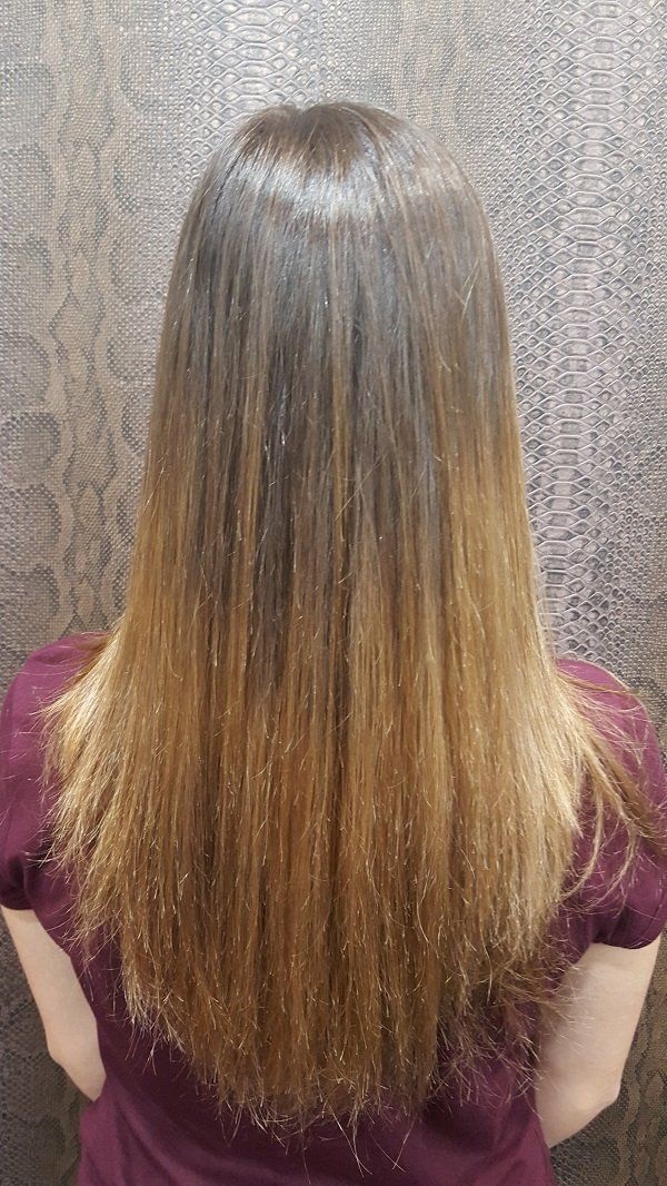 La parte posterior de la cabeza de una mujer con cabello largo y una camisa morada.