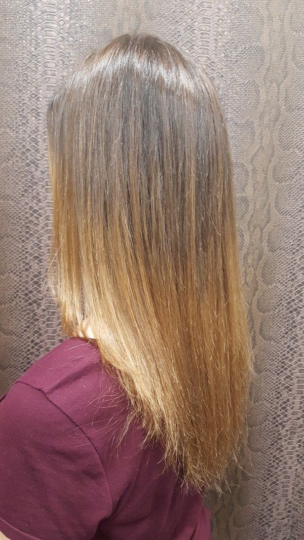 Una mujer con cabello largo y rubio está parada frente a una pared.