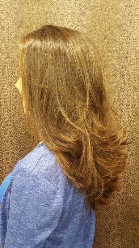 Una mujer con cabello largo y castaño lleva un suéter azul.