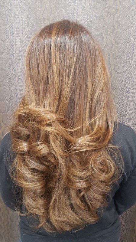 La parte posterior de la cabeza de una mujer con cabello largo y rizado.