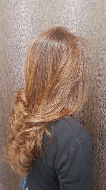 Una mujer con cabello largo y rubio está parada frente a una pared.