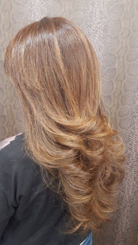 Una mujer con cabello largo y rubio está sentada frente a una pared.