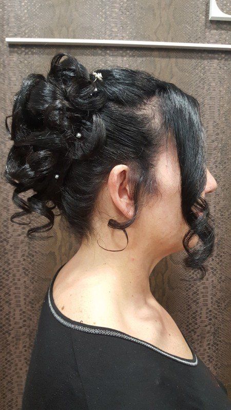 Una mujer lleva el pelo recogido en un moño con perlas.