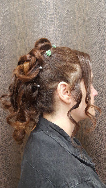 Una mujer con cabello rizado lleva una chaqueta negra y tiene el pelo recogido en un moño.