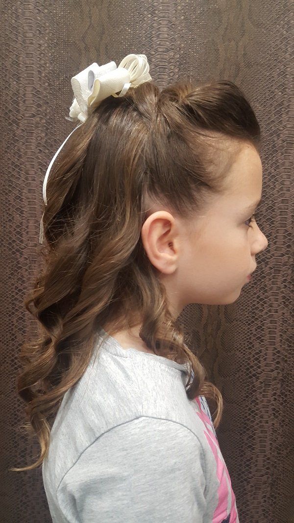 Una niña con pelo largo y un lazo blanco en el pelo.