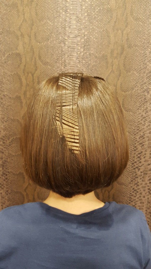 La parte posterior de la cabeza de una mujer con cabello corto y una camisa azul.