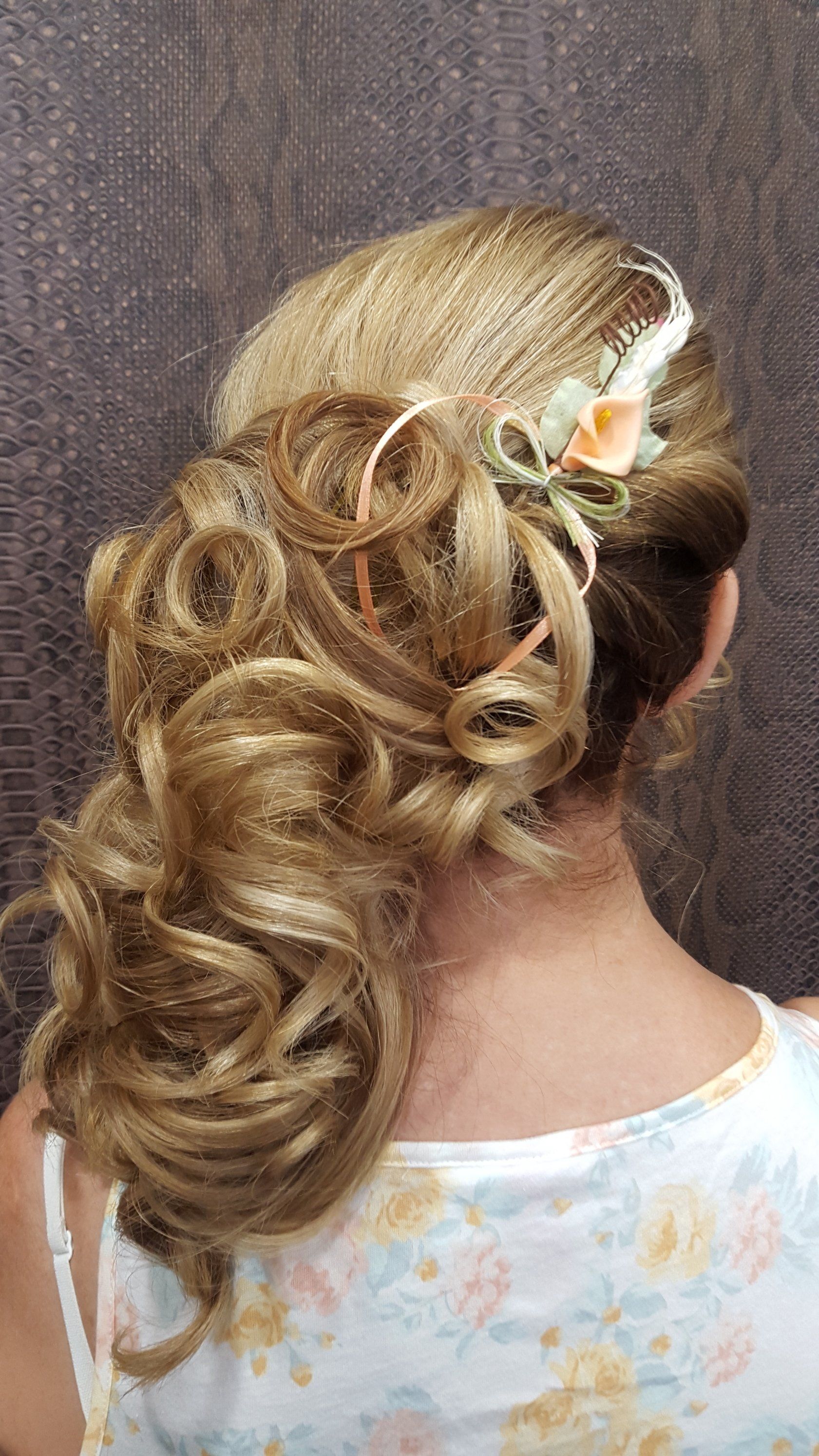 Una mujer lleva el pelo recogido en un moño con una flor en él.