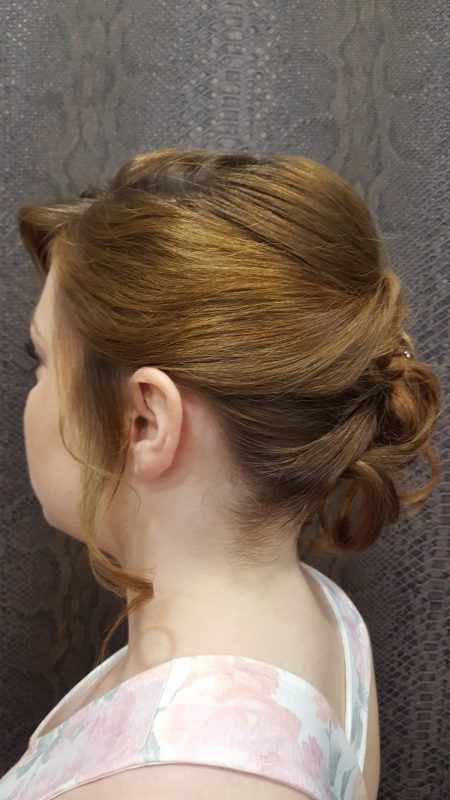 Una mujer lleva una camiseta rosa sin mangas y tiene el pelo recogido en un moño.