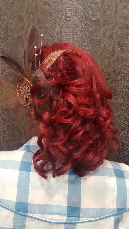 Una mujer con cabello rojo y una pluma en el cabello.