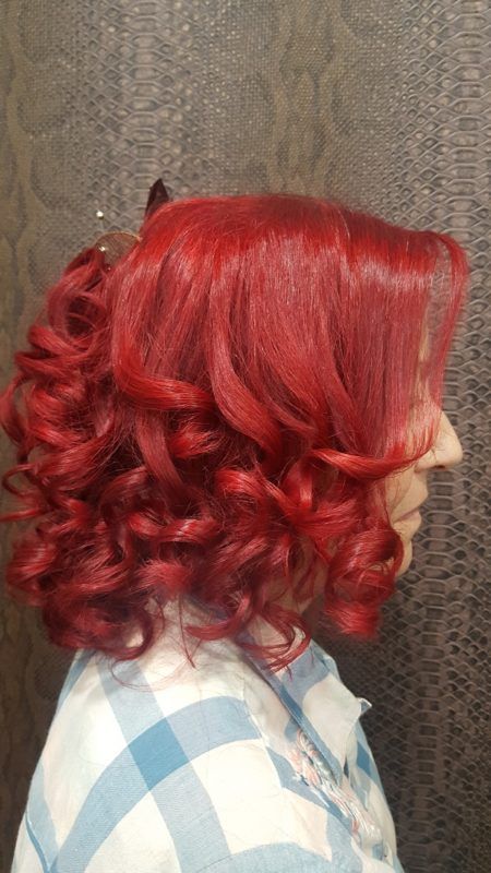 Una mujer con cabello rojo y rizado lleva una camisa a cuadros.