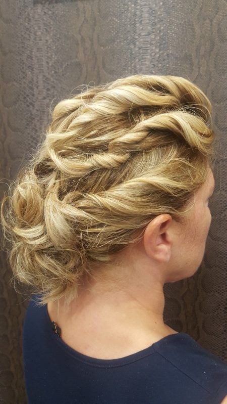 Una mujer con cabello rubio recogido en un moño trenzado lleva una camisa azul.