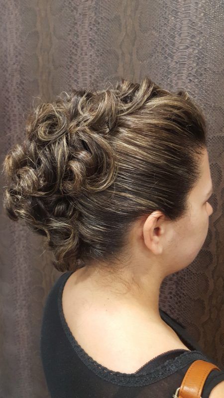 Una mujer con cabello rizado lleva una camisa negra y un cinturón marrón.