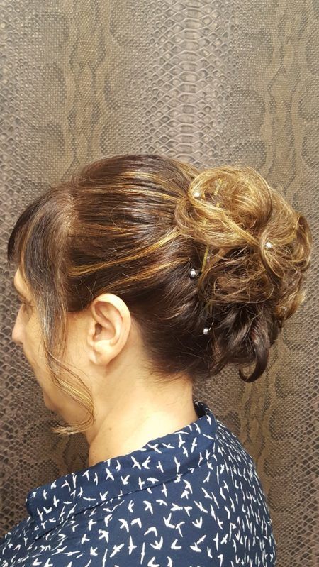 Una mujer lleva el pelo recogido en un moño con perlas.