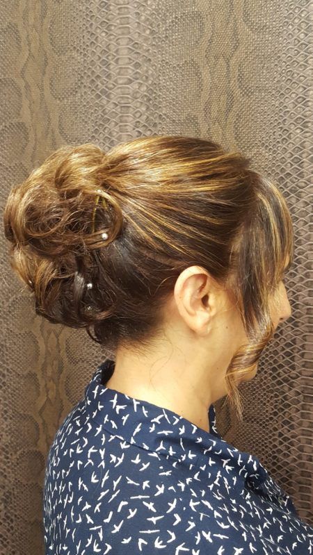 Una mujer lleva una camisa azul y tiene el pelo recogido en un moño.