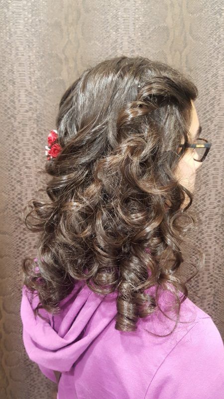 Una chica joven con cabello rizado y gafas lleva una sudadera con capucha morada.