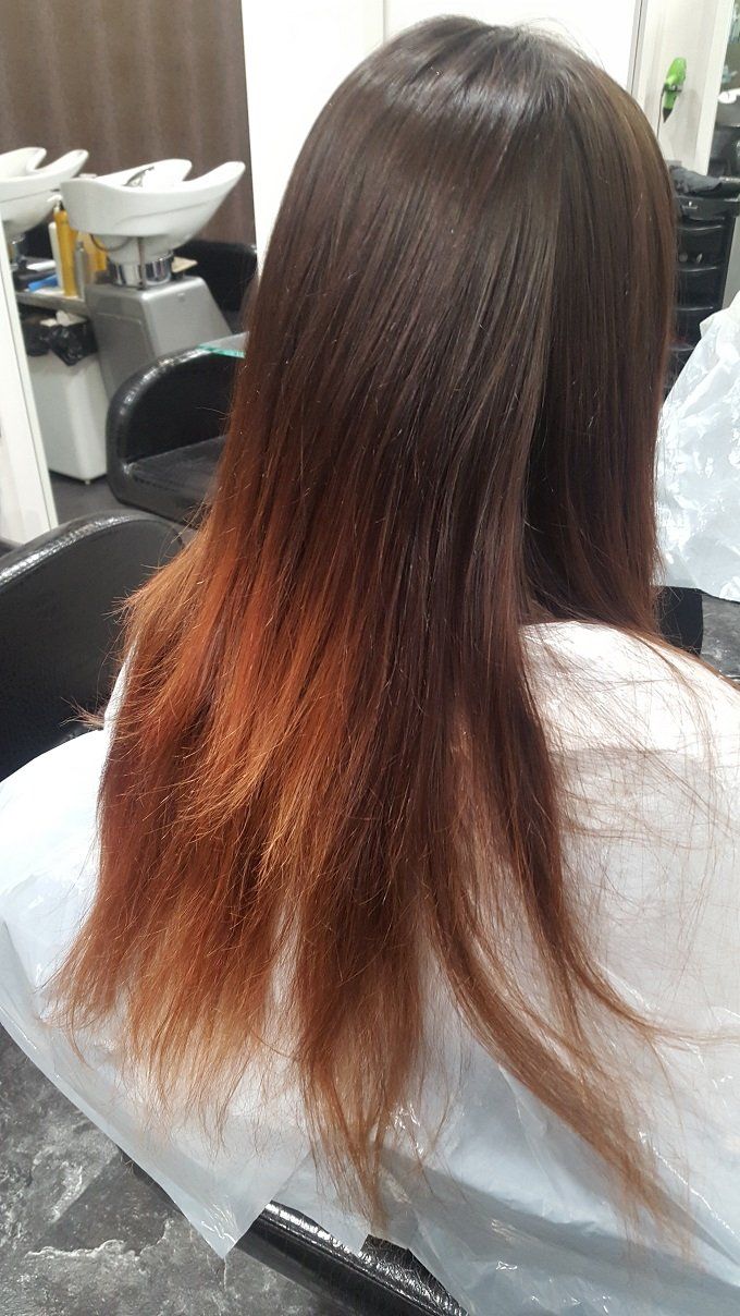 Una mujer con cabello largo está sentada en una silla en un salón.