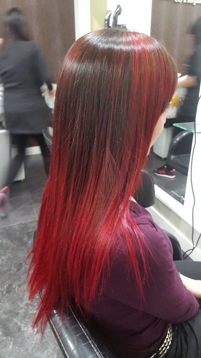 Una mujer con cabello largo y rojo está sentada en una silla en un salón.