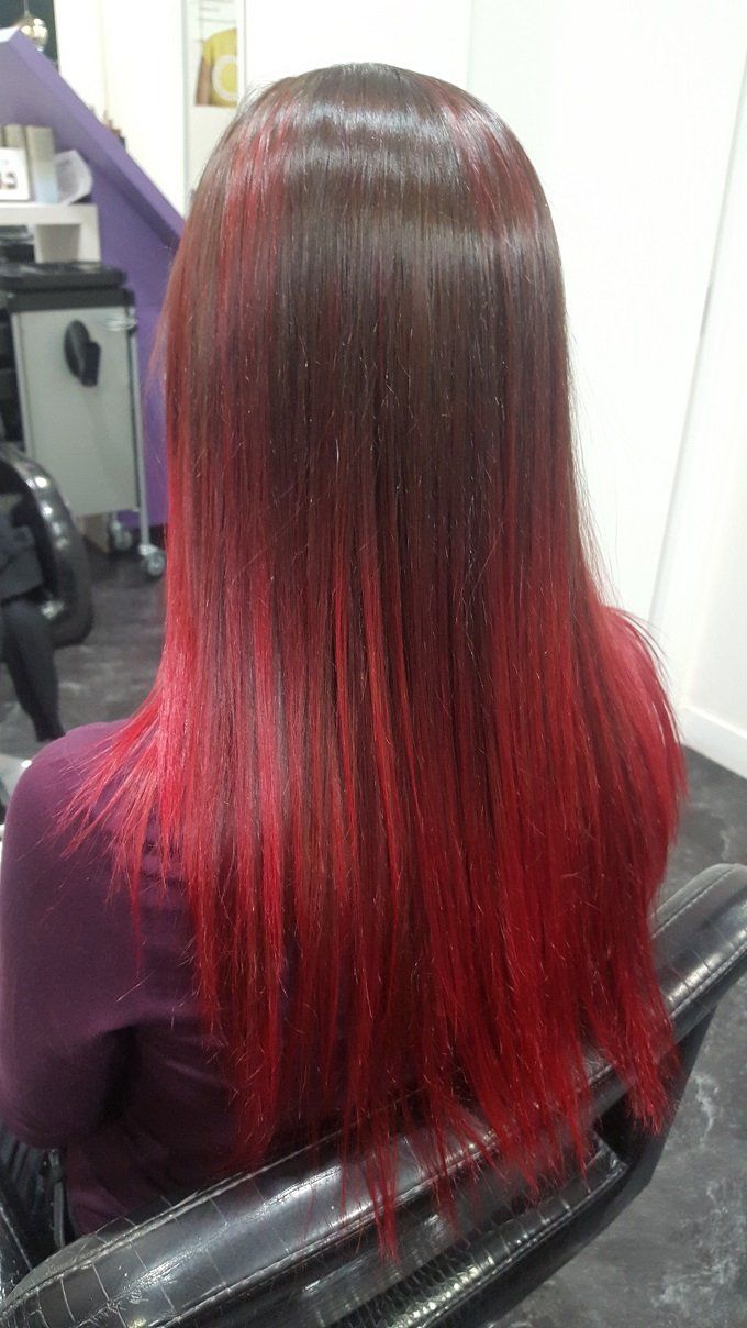 Una mujer con cabello rojo está sentada en una silla en un salón.