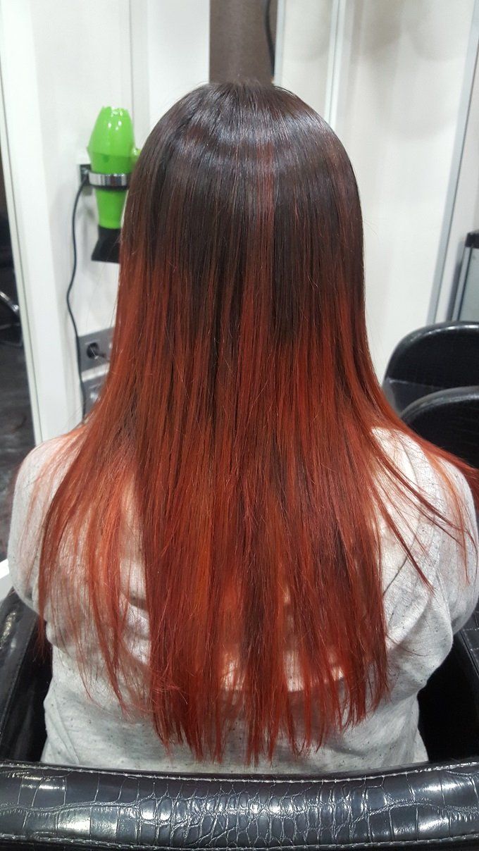 Una mujer con cabello largo y rojo está sentada en una silla en un salón.
