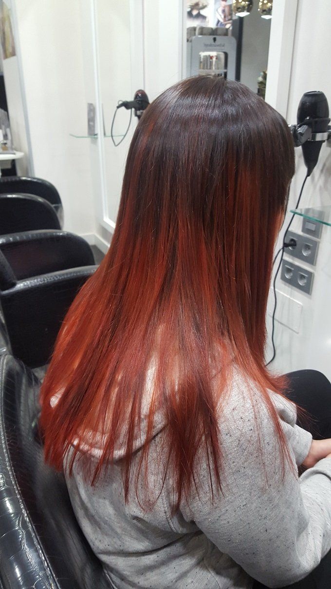 Una mujer con cabello rojo está sentada en una silla en un salón.