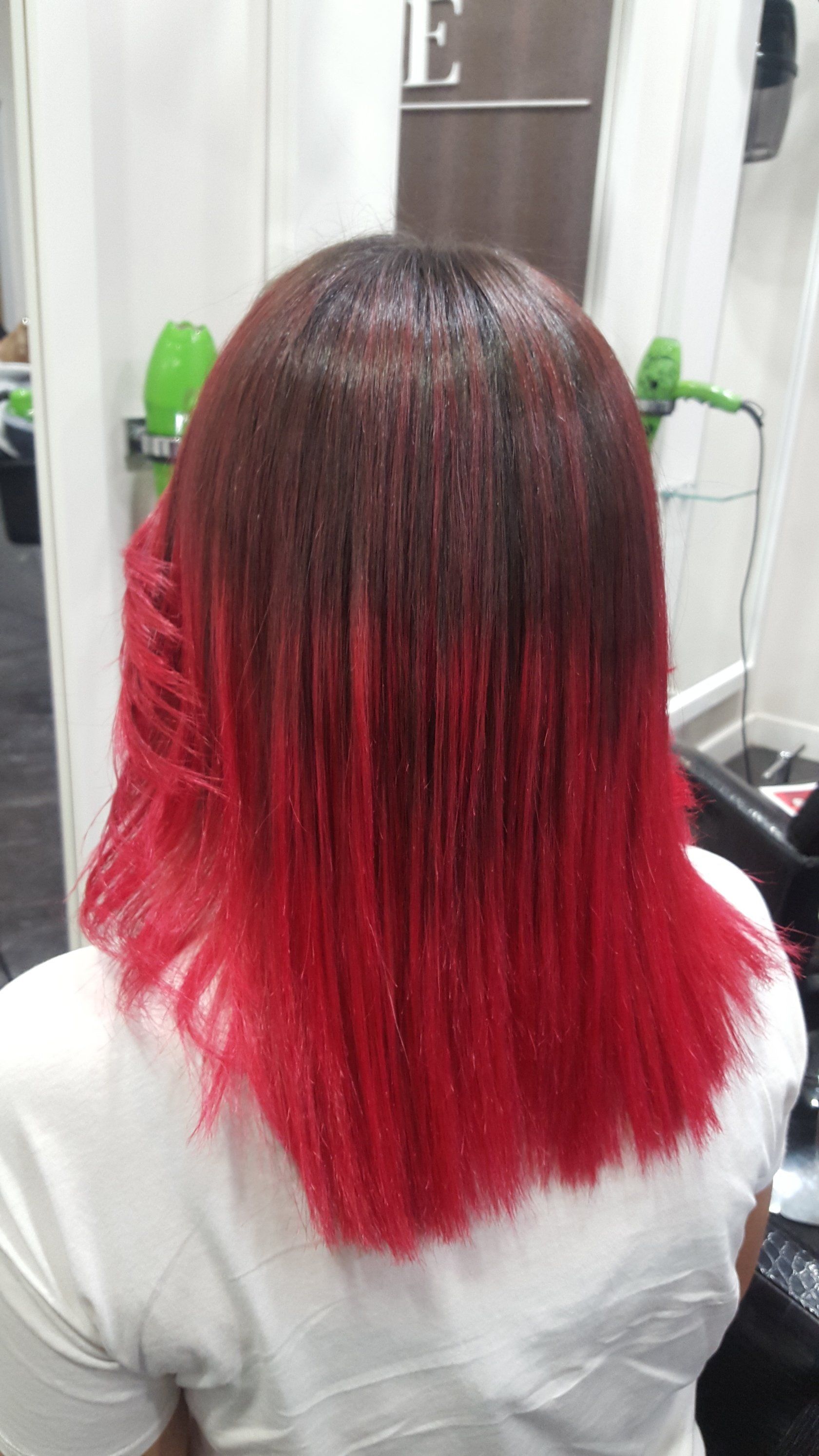 Una mujer pelirroja se está tiñendo el pelo en un salón.