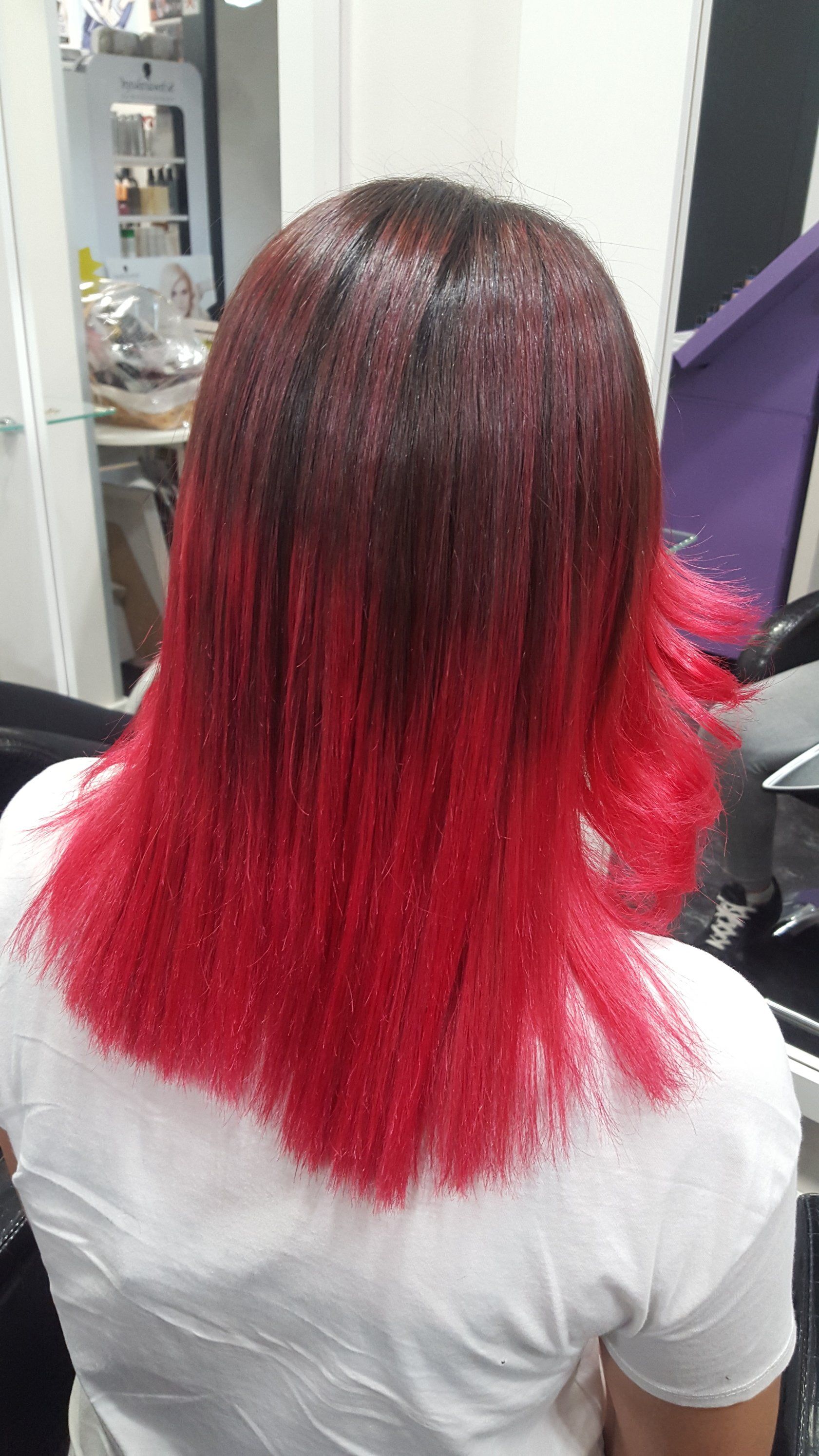 Una mujer con cabello rojo está sentada en una silla en un salón.
