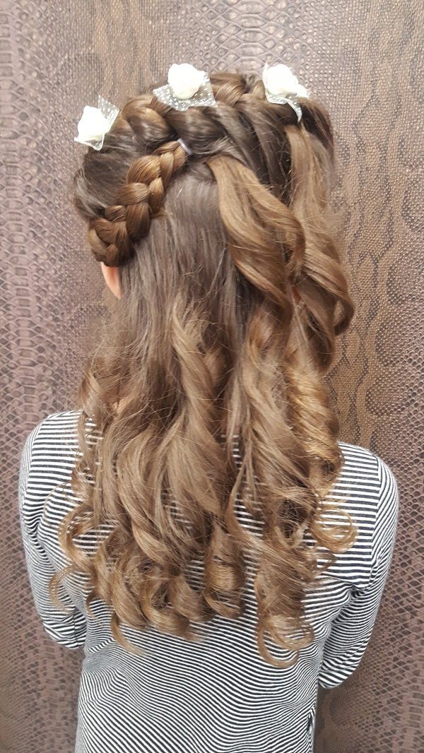 La espalda de una niña con un peinado trenzado y flores en el pelo.