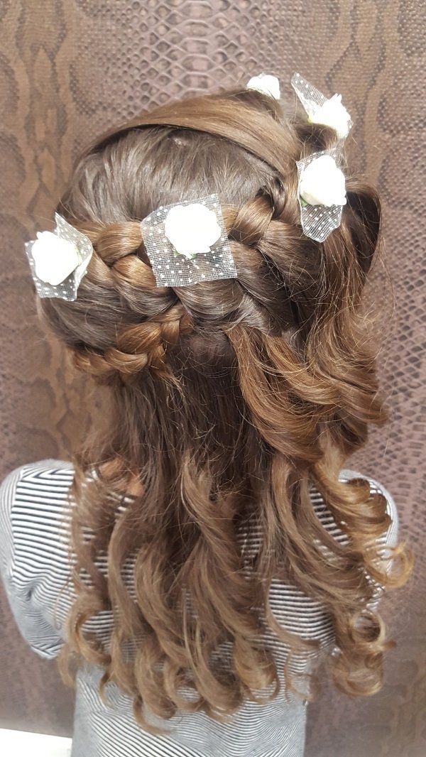 Una niña lleva un peinado trenzado con flores en el pelo.