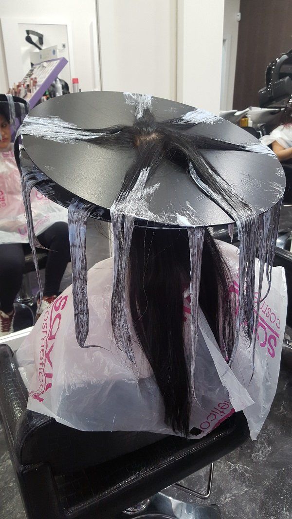 Una mujer se está tiñendo el pelo en un salón.