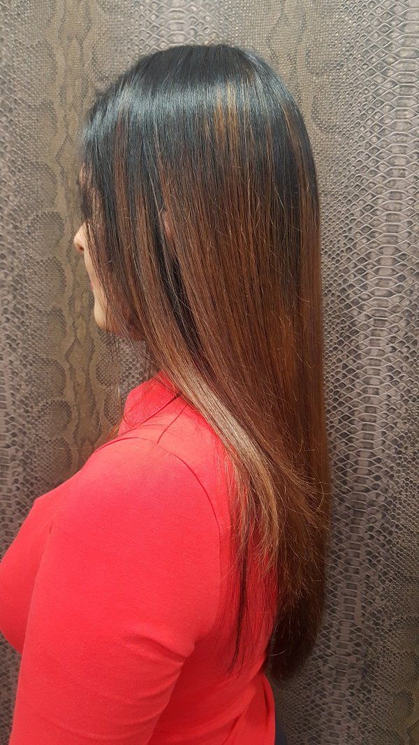 Una mujer con cabello largo lleva una camisa roja y está parada frente a una pared.