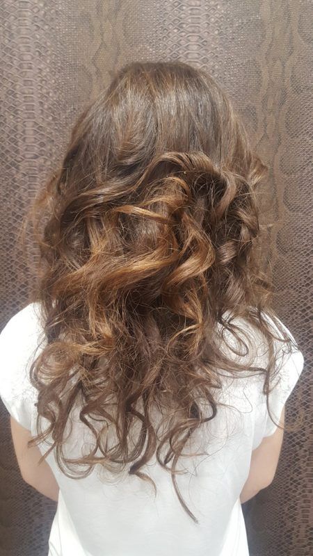 Una mujer con cabello largo y rizado lleva una camisa blanca.