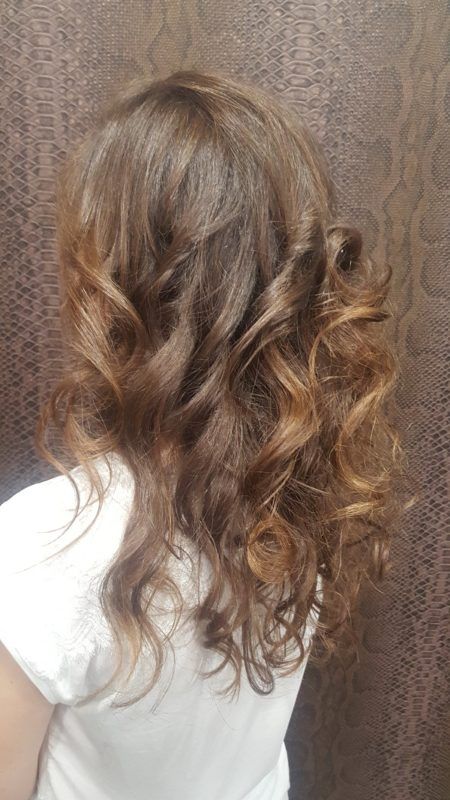 Una niña con pelo largo y rizado lleva una camisa blanca.